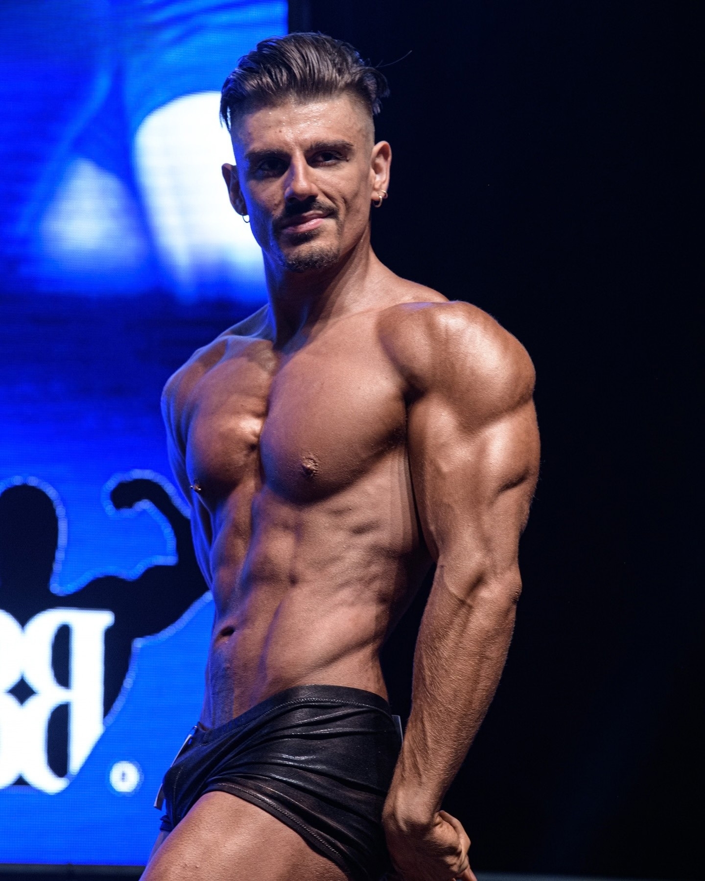 Enzo Farsetti in posa a doppio bicipite durante una competizione di natural bodybuilding